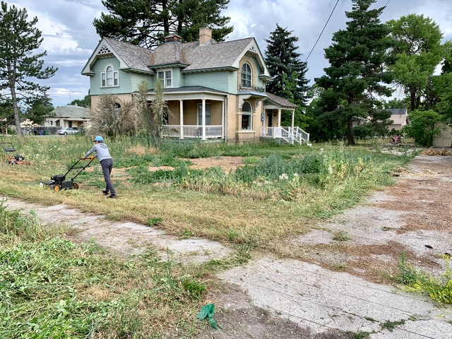 mowing an overgrown lawn of a historic house